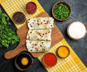 top-view-delicious-qutabs-cooked-dough-slices-with-greens-different-seasonings-grey-space_140725-75792